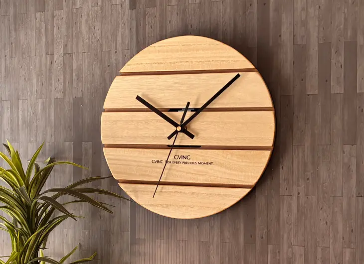 レーザーカッターで制作した円形の木製壁掛け時計。温かみのある桐の板に水平方向のスリットを施したモダンなデザイン。